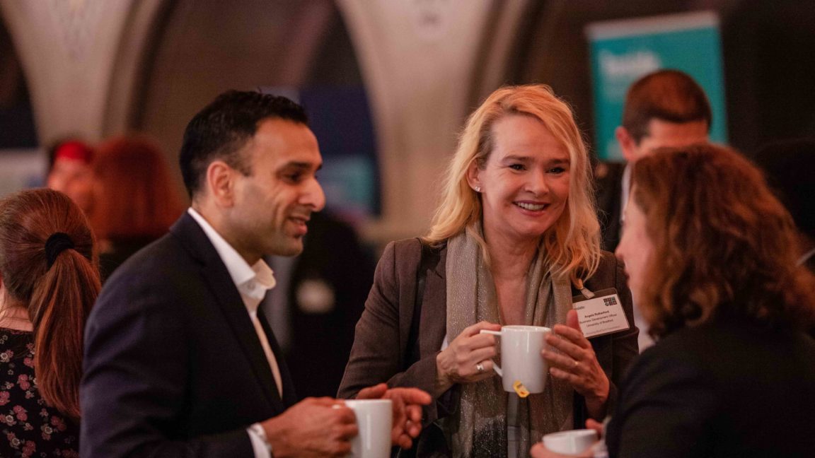 A picture of a man and two women in professional dress talking at a medtech conference